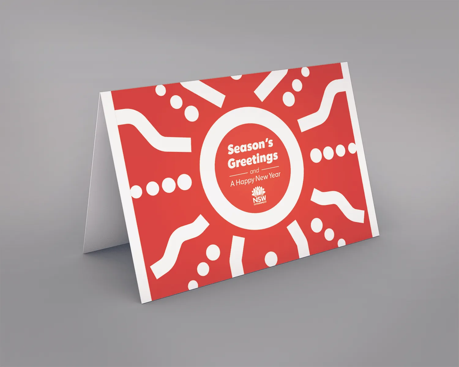'Season's Greetings' card mockup in solid red with a white sun-ray and dot motif